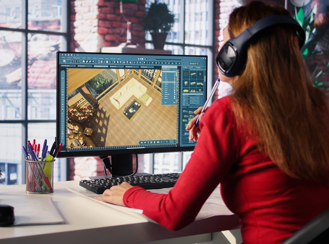 Female employee creates 3D render of an apartment interior using blueprints and architectural software. Employs computer aided tools and models to allow customization of flooring. Camera B.